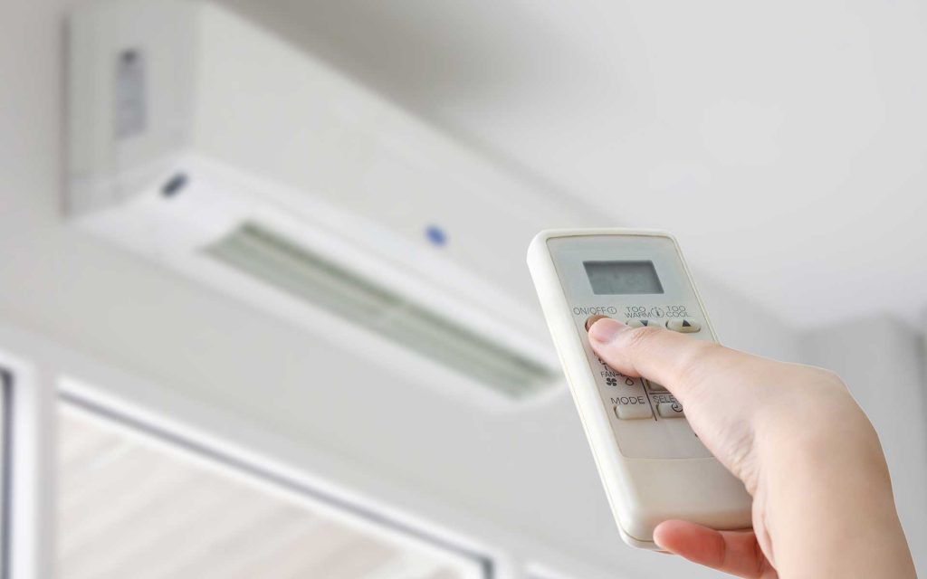 Person using remote control to power on a heating and cooling unit