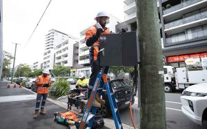 Workers mounting an EV charger and power supply on a pole in inner-city Sydney
